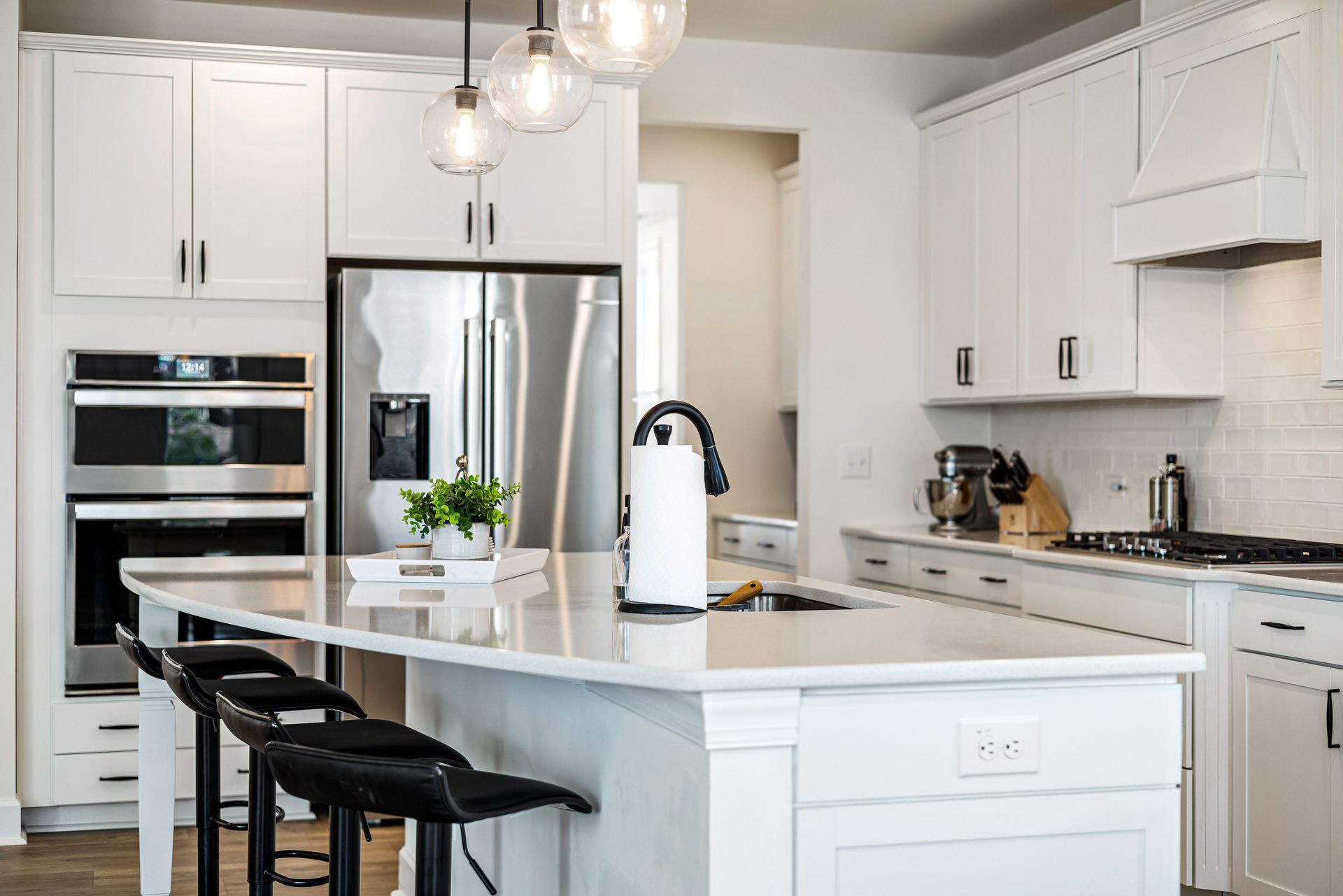 A sleek modern kitchen with white cabinets, elegant lighting, and stainless steel appliances, providing a clean and contemporary look.